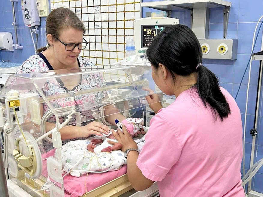 Two women are looking after a newborn baby in an incubator