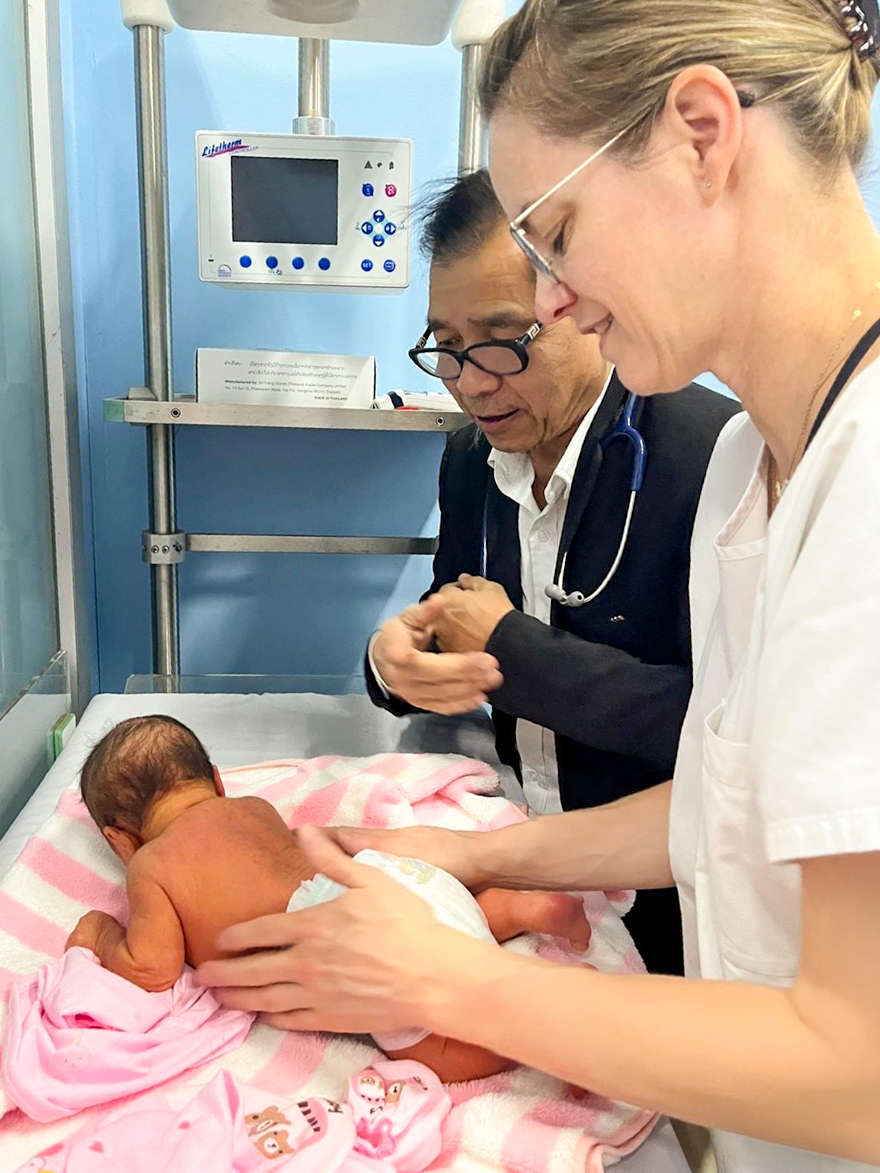 Two healthcare professionals are treating a newborn baby